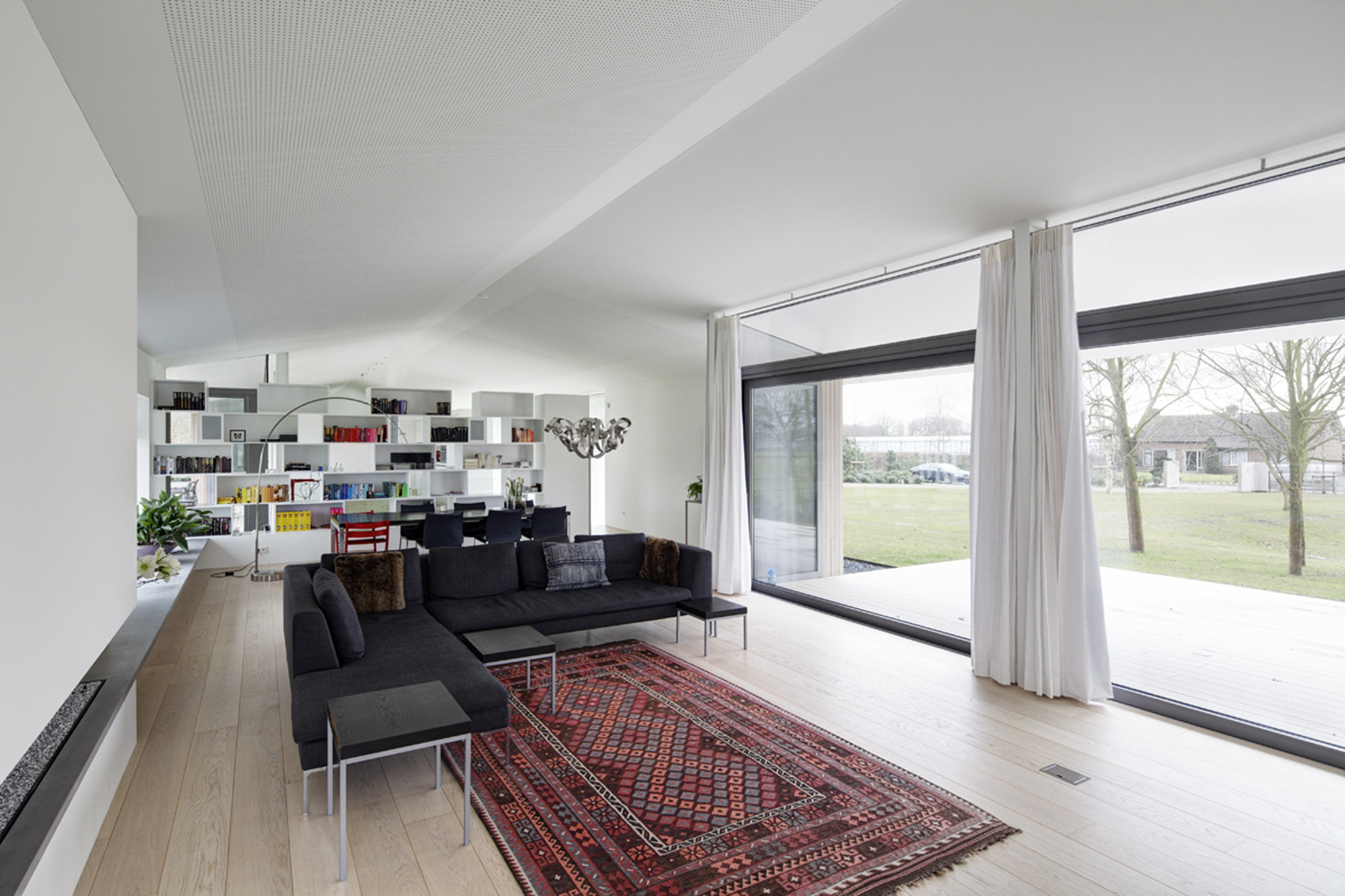 Red Colored Floor Carpet Along With Several Clear High Curtains
