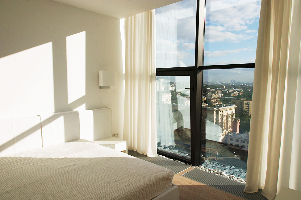 Bright Bedroom Interior Lightened Aside Natural Sunlight From Large Glass Window On Falcons Nest Penthouse Near Cream Curtain Bright Bedroom Interior Lightened Aside Natural Sunlight From Large Glass Window On Falcons Nest Penthouse Near Cream Curtain